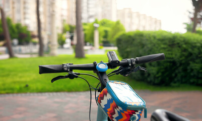 Fototapeta na wymiar Bicycle close up against park background. Handlebar with accessories.