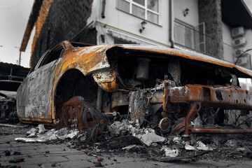 Fototapeta na wymiar A burnt-out destroyed car near a civilian building. The result of mortar shelling during the Russian-Ukrainian war.