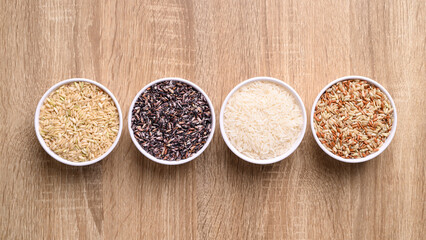 Thai rice seed (brown, white and purple) in bowl on wooden background, Table top view