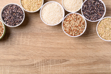 Thai rice seed (brown, white and purple) in bowl on wooden background, Table top view