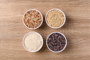 Thai rice seed (brown, white and purple) in bowl on wooden background, Table top view