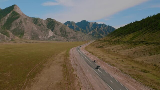 Mountains of Altai with traffic cars on Chuya highway, Siberia, Russia. Beautiful summer nature landscape at during daytime. Aerial view from a drone