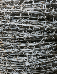 closeup of old unused twisted barbed wire roll with dirt, abstract background