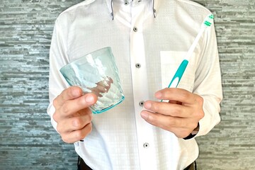 歯ブラシとコップを持つ男性