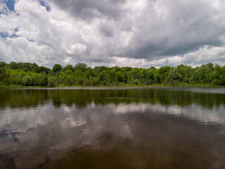 Large clouds are reflected in a small lake in cottage county in Ontario, Canada.