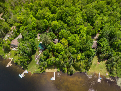 An aerial view looking down on several cottages and their swim docks.