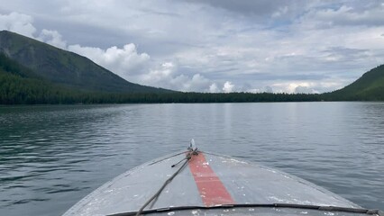 Motorboat on Multin lakes in middle of mountains under dramatic sky in Altai, Siberia, Russia. Beautiful summer nature landscape at pre storm daytime