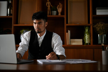 Professional asian businessman or male CEO in formal suit working at his desk, using laptop