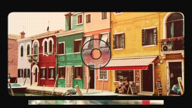 Burano, Venice, Italy - July 2, 2022: Retro photo camera screen with brightly colored houses and water canal with boats in Burano, people walk and rest on streets