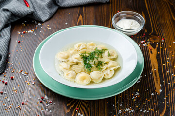 Dumplings in the soup and bullion on wooden table