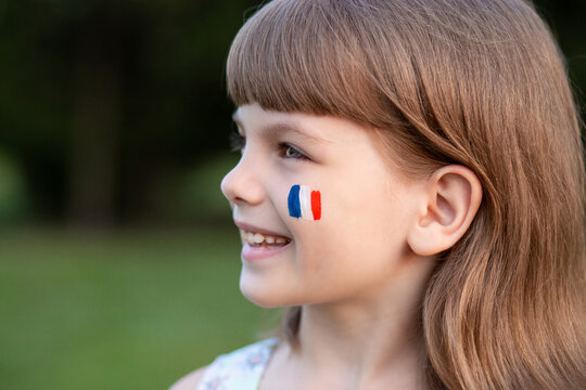 Portrait of child with painted French flag, closeup. Kid fan with blue white red flag painted on face. Education abroad. 14 July, Bastille day, main France national holiday