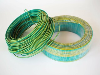 Green rolled electric cable on white background. closeup photo, blurred.