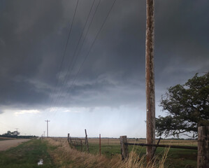 Utility Pole, Fence and Rural Gravel Road with Gray Storm Clouds Overhead in Oklahoma