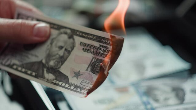Burning American dollar banknotes, Flame of fire from money. Rich person having stacks of 50 US dollars in metallic suitcase. Paper money loss, financial crisis and depressed economy. 