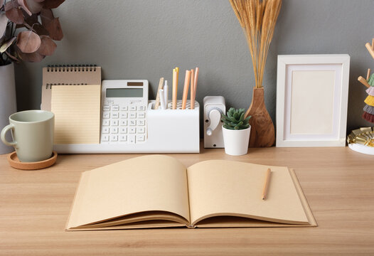 open kraft book on wood table with stationery