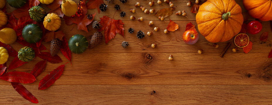 Thanksgiving Wallpaper with Autumn leaves, Gourds and Pine cones on a Natural wood Tabletop.