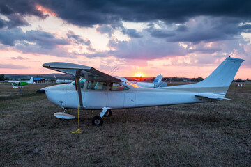 Fototapeta na wymiar Small private aircrafts parked at the airfield at picturesque sunset