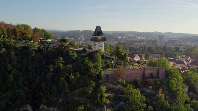 Aerial view across Uhrturm clock tower on Graz's Schlo&szlig;berg dolomite woodland hilltop and Graz city skyline
