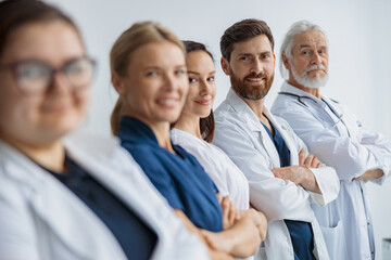Group of doctors standing in a line keeping arms crossed and looking camera at the modern clinic