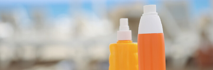 Orange plastic bottles and a beige towel on a beach lounger