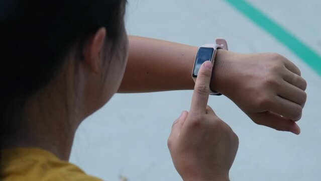 Close-up shot of a female runner counting calories burned on a smart watch. A young athlete uses a smartwatch to check results while practicing outdoors.