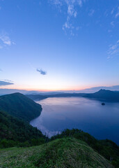 Naklejka na ściany i meble 山間の湖の夜明け。日本の北海道の摩周湖で。