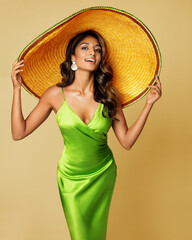 Woman in Big Summer Hat. Mexican Girl in Sombrero Hat. Fashion Model in Green Silk Dress over...