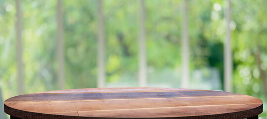 wooden round  table background with blur window see through garden at home.Mockup banner space for...