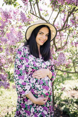 a pregnant girl in a dress near the sakura in the garden