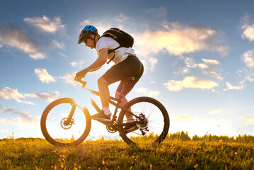 Professional mountain bike cyclist riding a in nature on the sunny sky background.	Active healthy...