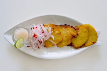 Peruvian food: Corn cakes with spicy onion sarsa and lemon juice. Top view.
