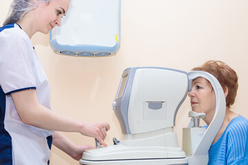 A girl optometrist examines the eyes of a patient using special modern equipment