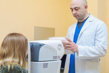 A male ophthalmologist checks the eyesight of a young girl using a modern vision tester