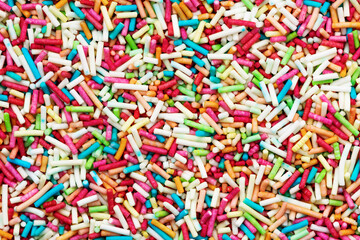 Texture of candy multi colored sprinkles. Rainbow coloured sprinkles background.