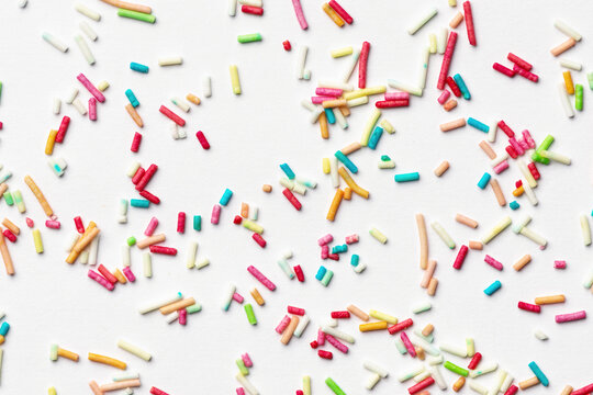 Candy multi colored sprinkles background. Rainbow coloured sprinkles on white background.