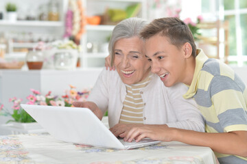 Grandmother with her grandson using laptop at home