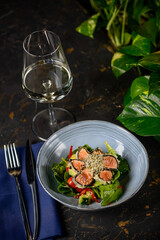 salad with tuna in batter in a blue plate on the table with wine utensils
