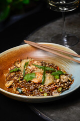 Thai buckwheat noodles with shrimp in a plate on a gray background of a chair