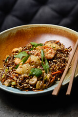 Thai buckwheat noodles with shrimp in a plate on a gray background of a chair
