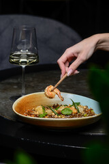 Thai noodles with shrimp decorated with green tiles in his hands holds a shrimp