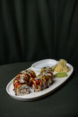 sushi roll with avocado in a white plate on a dark background