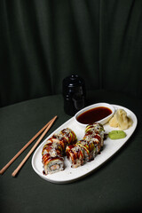 sushi roll with avocado in a white plate on a dark background with chopsticks