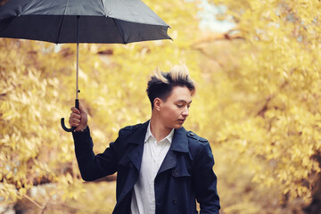 Autumn rainy weather and a young man with an umbrella