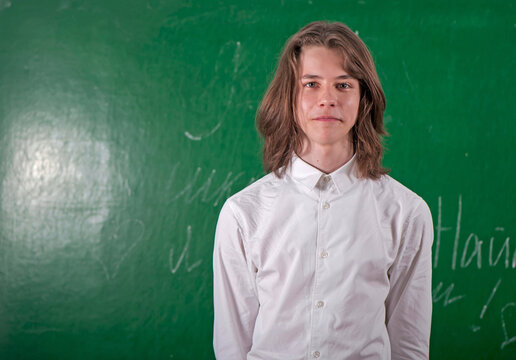 Schoolboy in a white shirt answering at blackboard in classroom