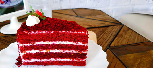 Piece of red velvet cake in white dish on wooden table at cafe. Sweet food or dessert on plate. 