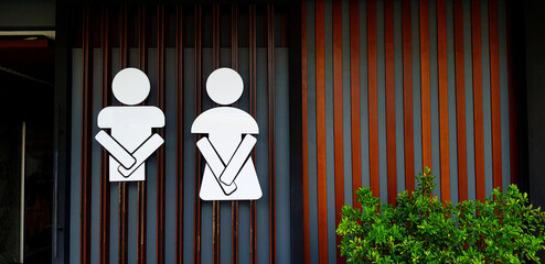 Public toilet sign or symbol of man and woman on wooden and gray or grey wall background with copy...