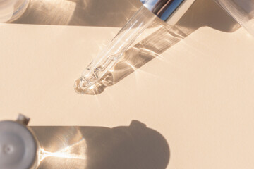 close up of pipette with pouring liquid serum with bottles and graphic shadows