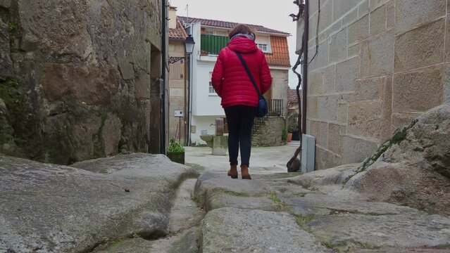 Woman walking through narrow streets of Combarro, Spain. Gimbal, low POV