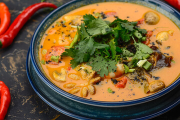 tom yum soup in a blue plate on a dark background macro photo
