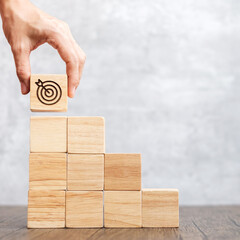 hand hold dartboard block over stack of building with business goal, strategy, target, mission,...